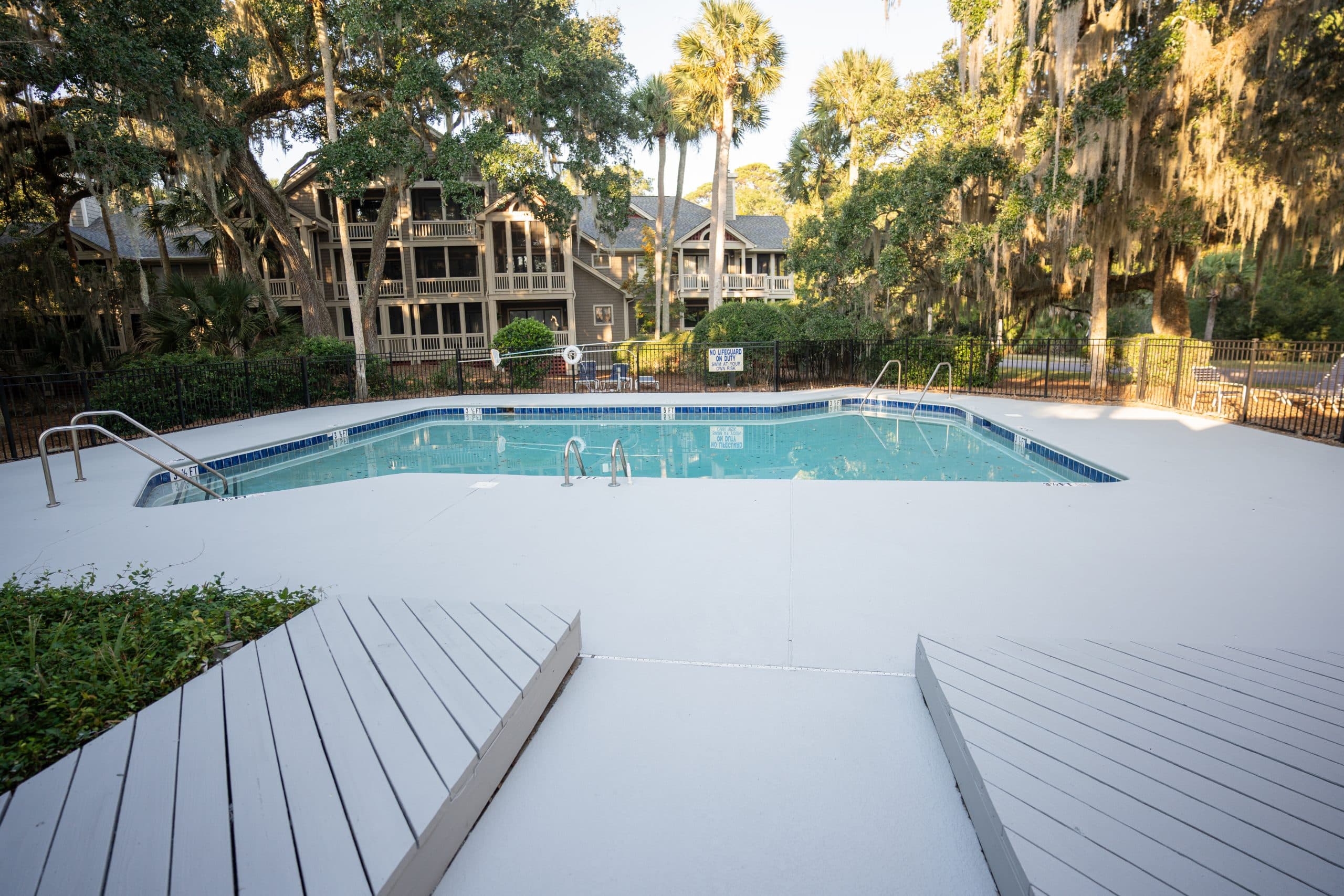 Resurfaced pool deck under Spanish-moss oaks at a residential property