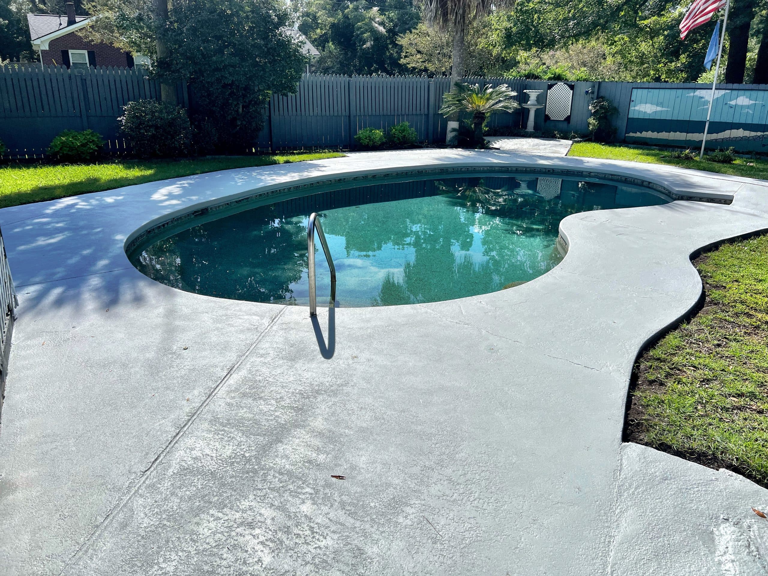 Kidney-shaped pool with concrete pool deck prepped for resurfacing